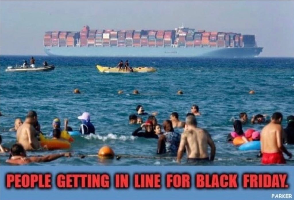 People on the beach with a cargo ship in the water. Captioned "People getting in line for black friday."